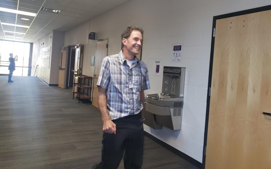 Mr. E laughing in the hall while being approached by Mr. Genzel. Mr. Engeldinger, a journalism teacher at New Ulm Public High School, is being approached by Mr. Genzel while journalism students have their phones out. 