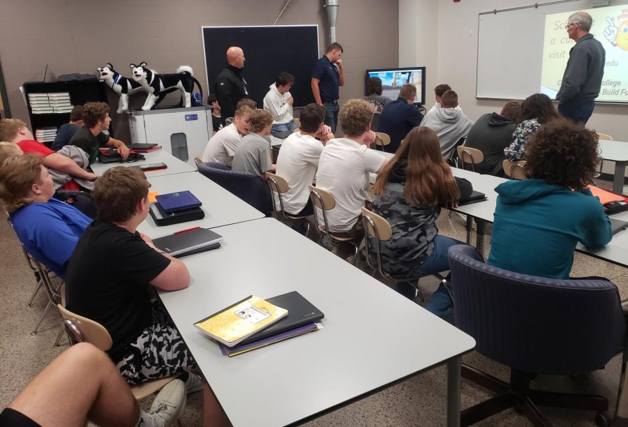 5th-hour Intro to Trades class looks on while student runs excavator simulator. 