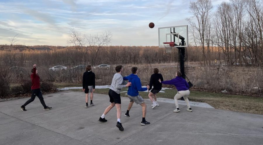 The boys basketball team plays basketball outside after their team meal. 