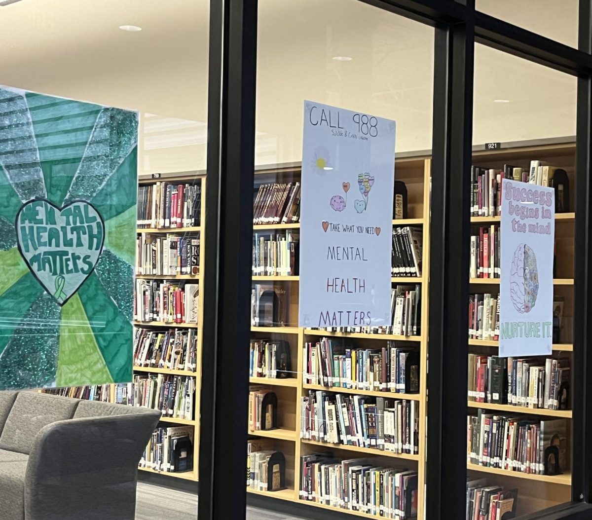 Posters made for Mental Health Awareness Week hung on the windows of the library. 