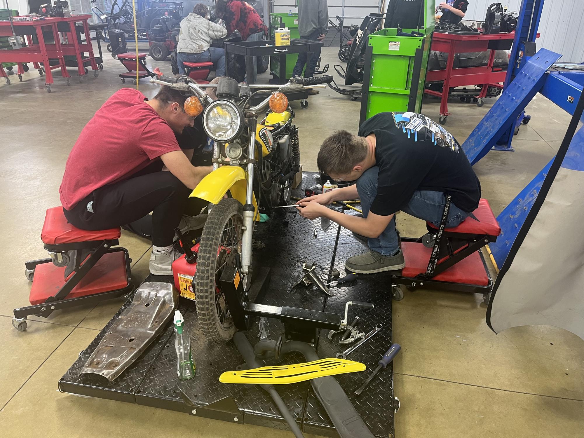 Brody Griebel, Ethan Goff, and Michael Powers (left to right) work to get the bike running a second time.
