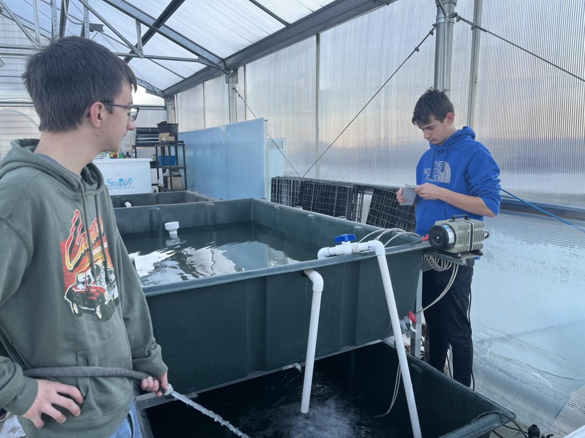 Dylan Portner and Tucker Berg (left to right)work on filling the aquoponics system with water.