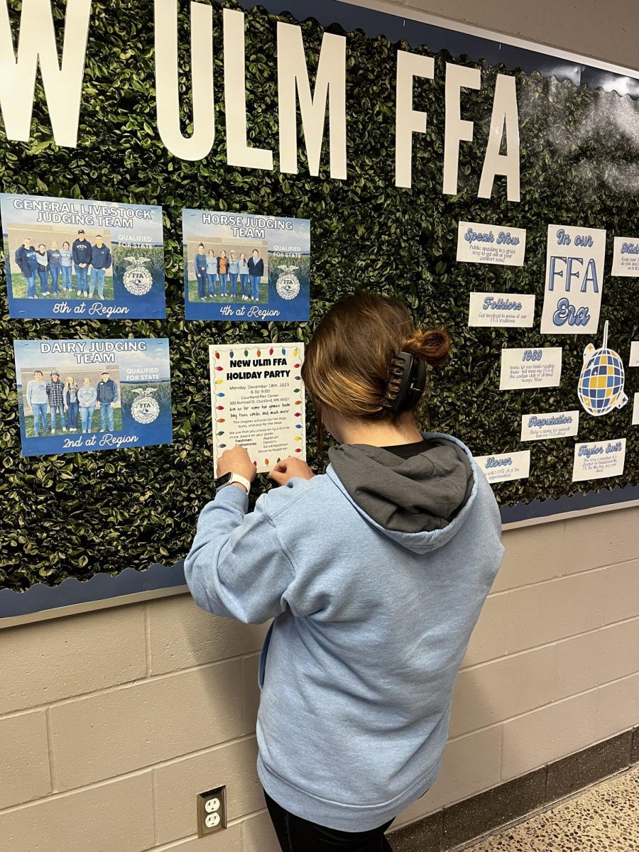 Sophomore Zelli Kamm hanging the poster advertising the FFA holiday party.