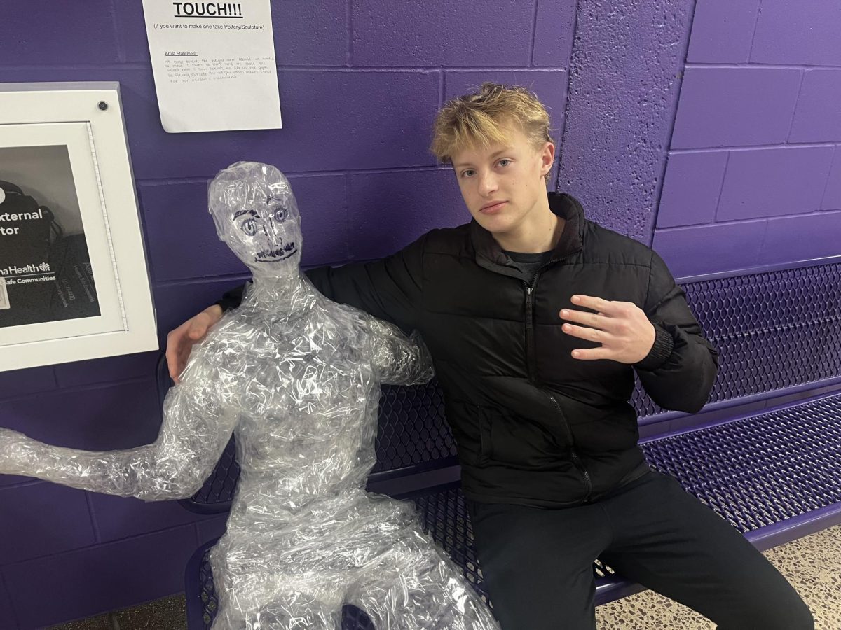 Junior Isaac Friese poses with pottery sculpture 