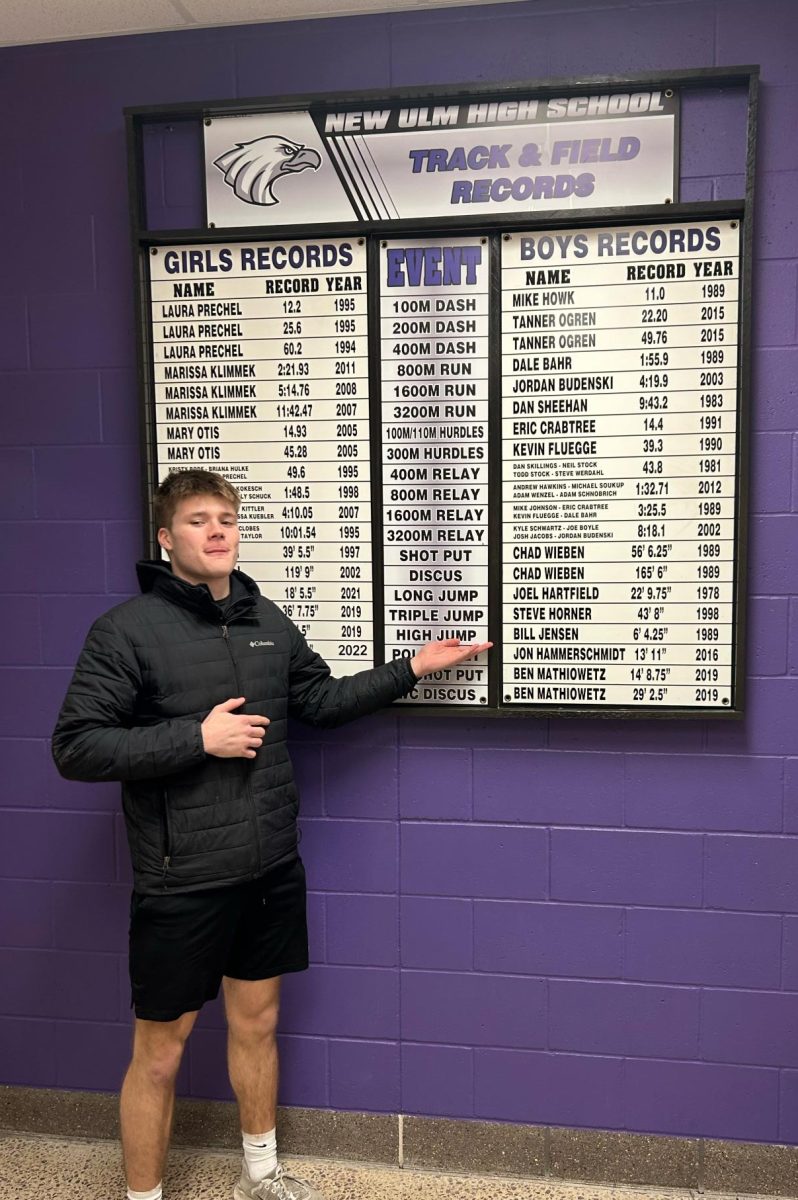 High jumper, James Osborne poses in front of the track record board.