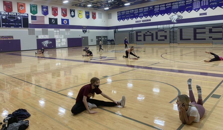 Varsity kick dancers social distance while stretching.