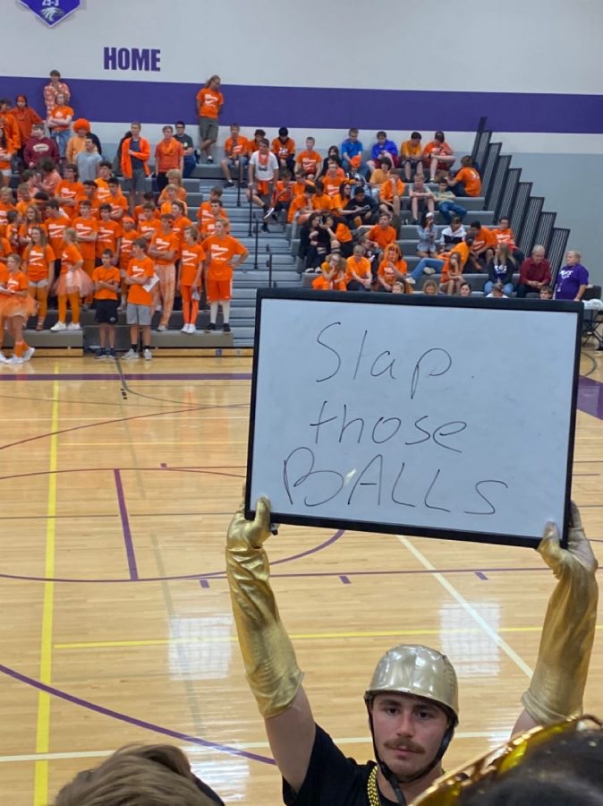 Senior, Jacob Martinka, holds a whiteboard that says "Slap Those Balls" during Ping Pong match.