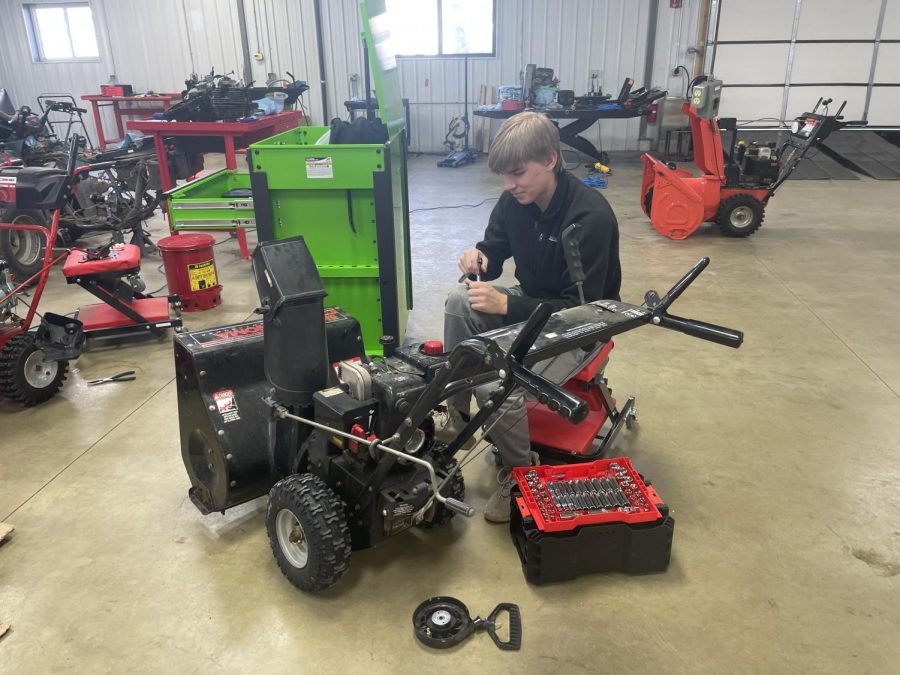 Student Cooper Jensen working on a snowblower 