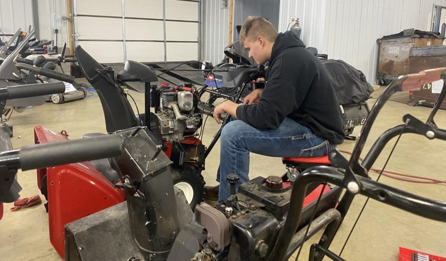 Senior Jarrett Platz works on a snow blower in Eagle Enterprise