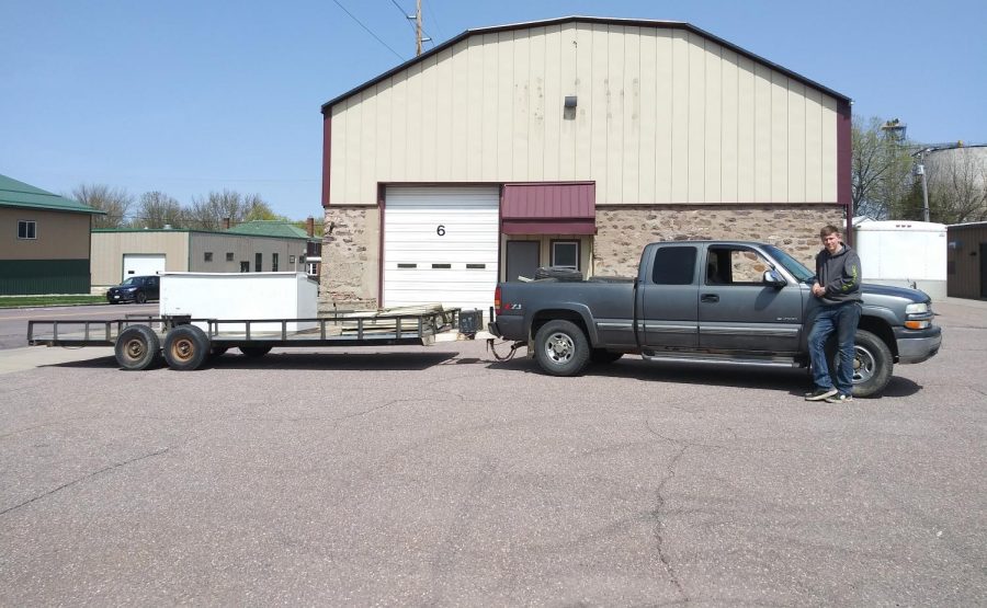 Jacob standing next to his truck and trailer used to haul scrap metal.