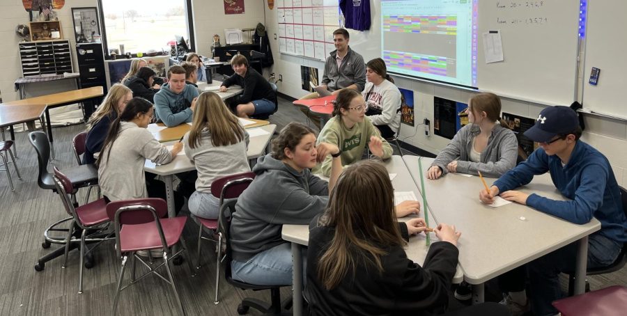 A shot of the Knowledge Bowl team practicing with Mr. Nelson reading.  "... When Mr. Bute asked me if I wanted to help him out I jumped on the opportunity! I really enjoy seeing kids use their brains outside of the classroom and be competitive," stated Mr. Nelson