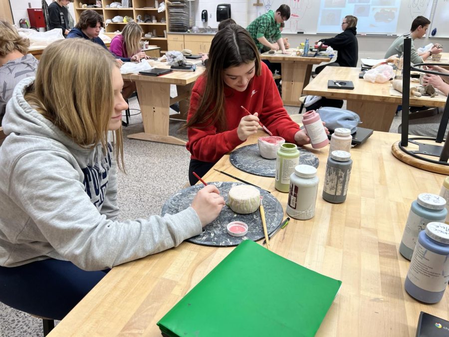 Junior Evelyn Schaefer (left) and Senior Bella Dunford glazing their pinch pots.