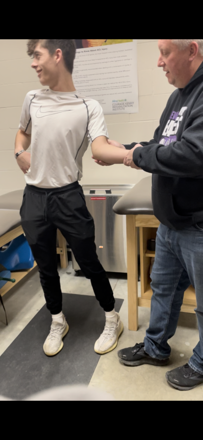 Marcus the athletic trainer testing how far Logan Lee's elbow will go