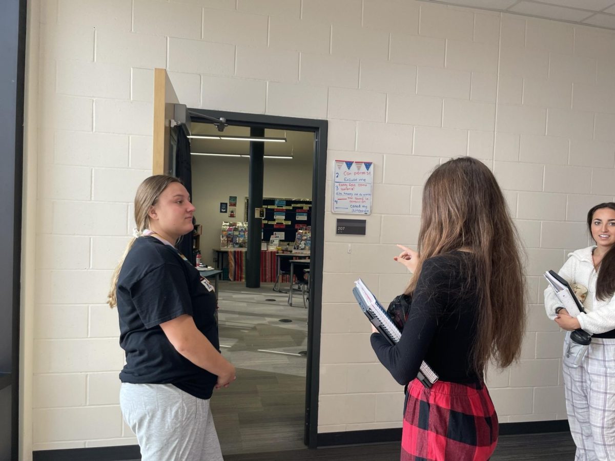 Student teacher Ms. Gregorious talks to senior Megan Hames before Spanish class. Hames is repeating the "contraseña" or password, which every student must say before entering the classroom.