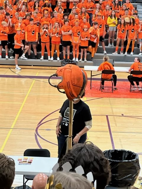 A senior mounts a freshmen students helmet on senior flag.