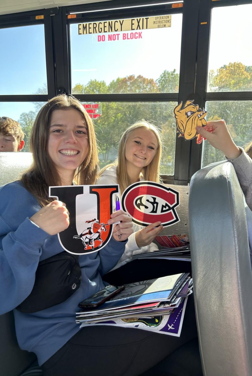 Juniors Shelby Seifert and Lauryn Ludewig holding stickers from the college fair.