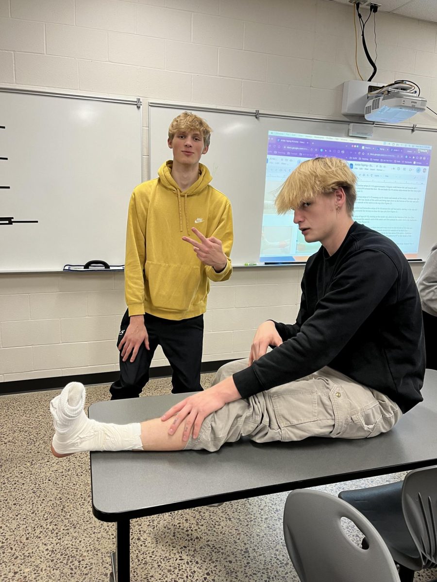 Seniors at work: Nate Firle just finished taping Tallak Rakowski's ankle.