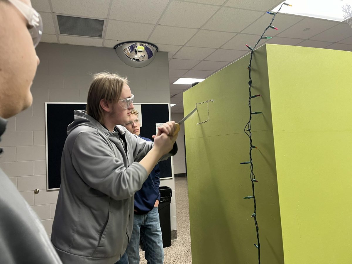 Senior Lincon Hoffmann cuts a hole in the science hall study station to make sure there is no wiring behind the sheetrock. 