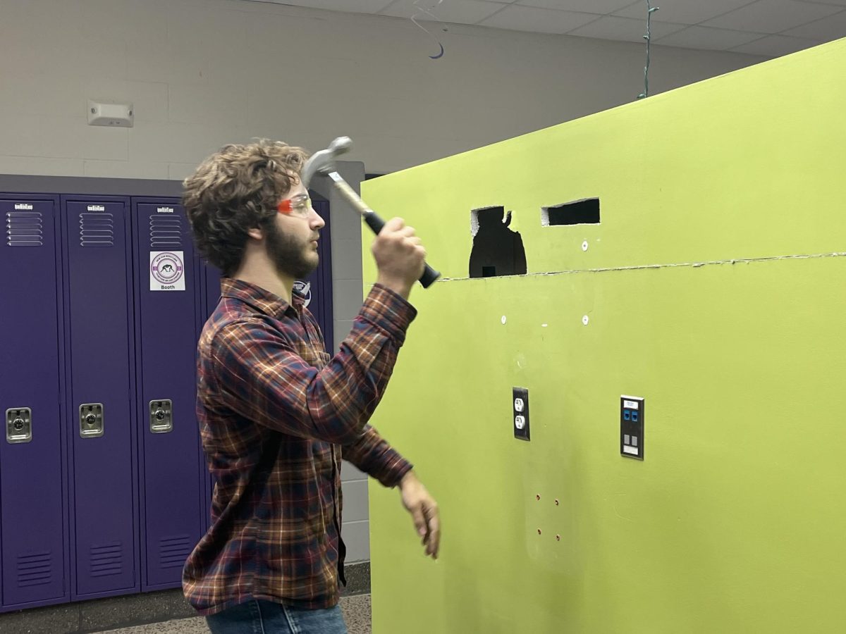 Senior Mark Beranek swings the hammer at the wall in the science hall. 