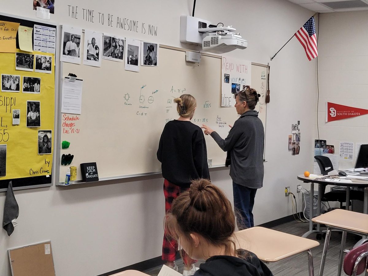 Study Skills for both students and teacher. Mrs. Cowing teaching her student geometry and also learning it for herself. Mrs. Cowing it the lady on the left at the board and the other people in the photo are her students. 