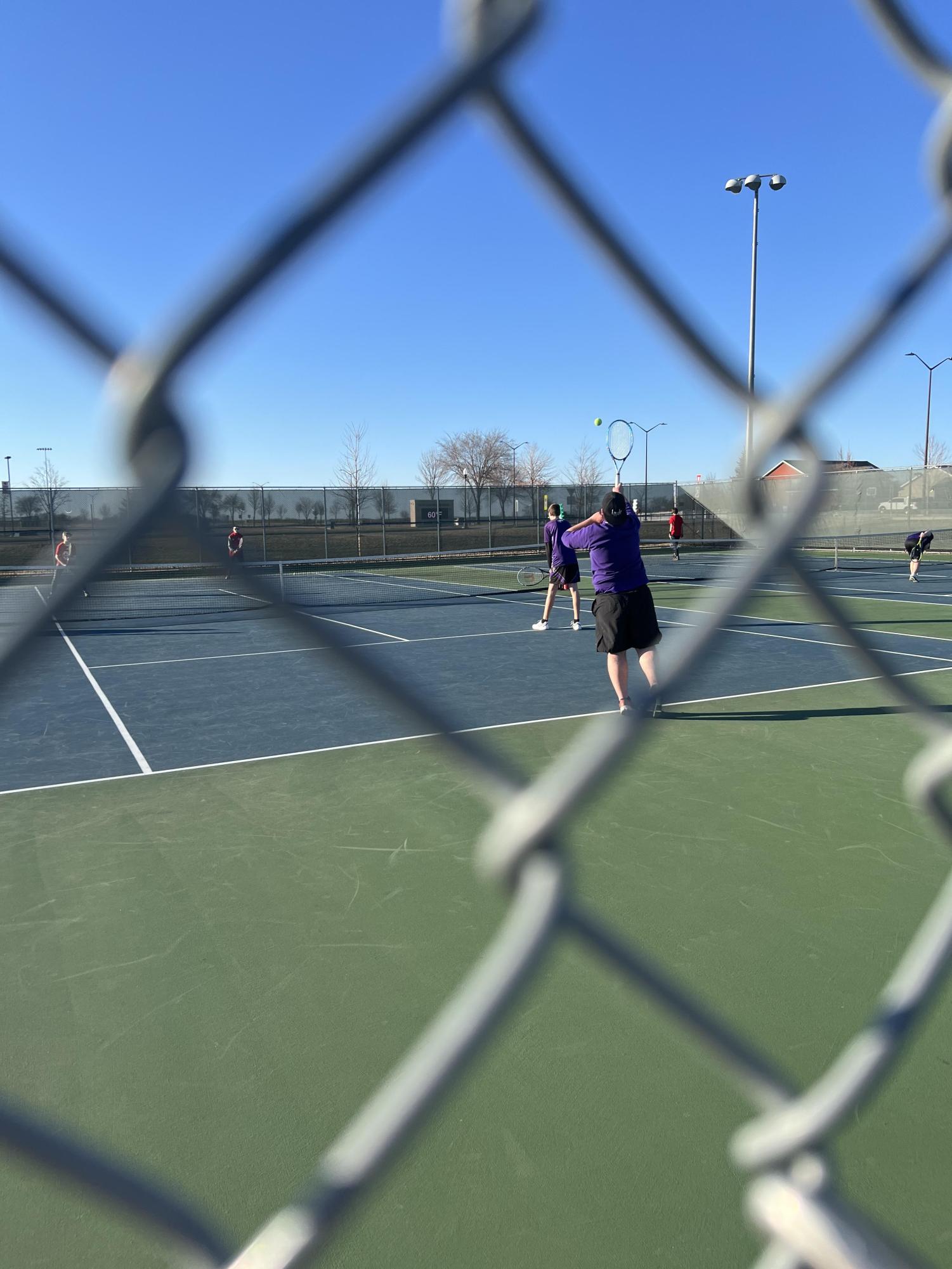 Bradley Trullinger hitting the ball on his serve against his opponents.