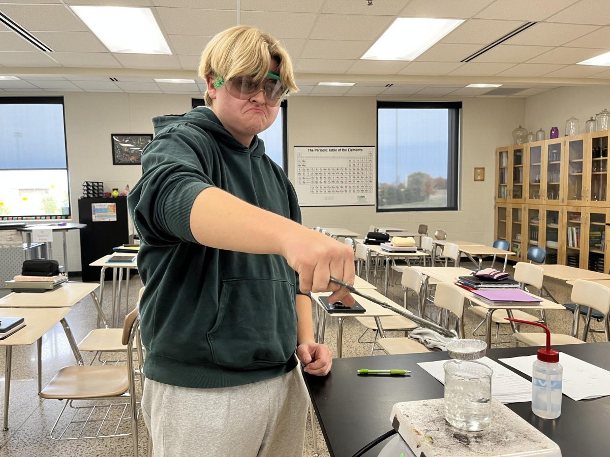 Junior, Everett Brown melting chemicals over a beaker of boiling water.