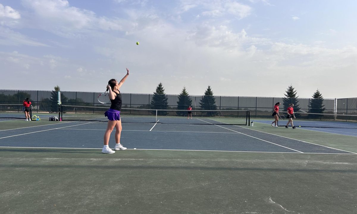 Freshman Natalie Fischer goes in for a serve against her Worthington opponent.