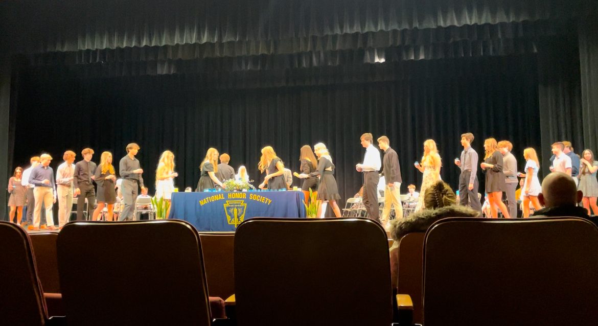 Students walk to place a candle that represents the National Honor Society at their induction night.