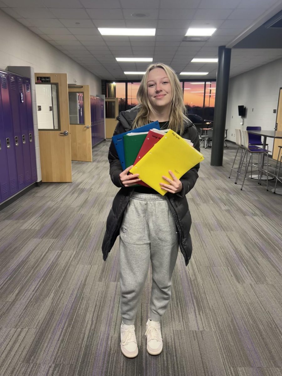 Junior Stella Fischer poses with folders that could all be considered the color of math.