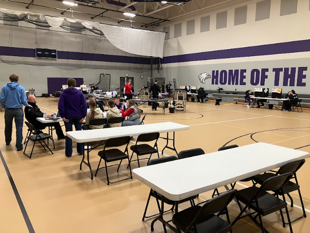 Students giving blood while students recover from giving blood with provided snacks and beverages.