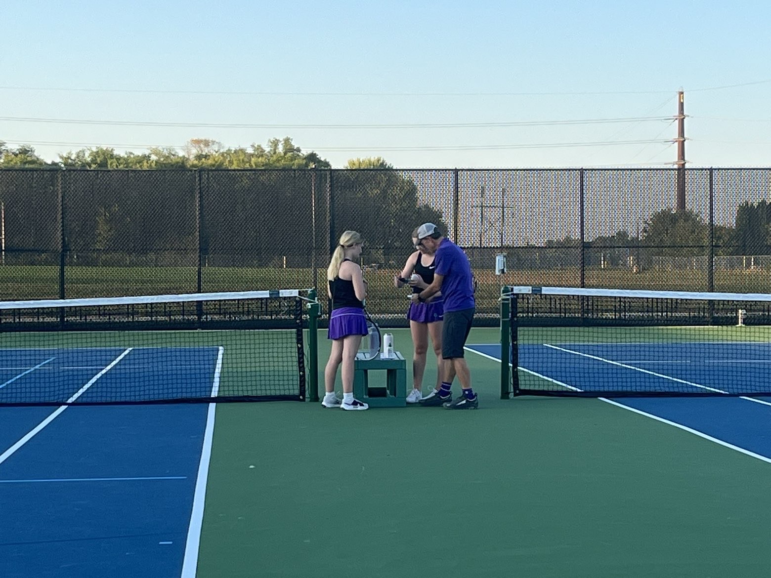 New Ulm tennis coach Mr. E talking to players middle of their game.