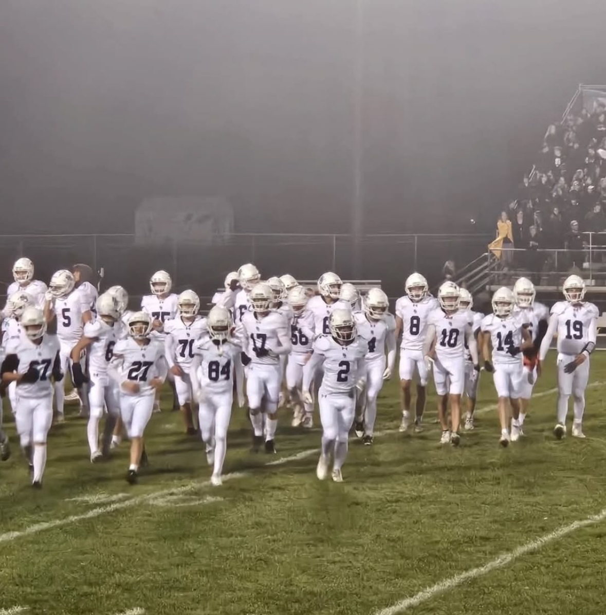 New Ulm football team jogs onto the field in preparation for their section game against Willmar