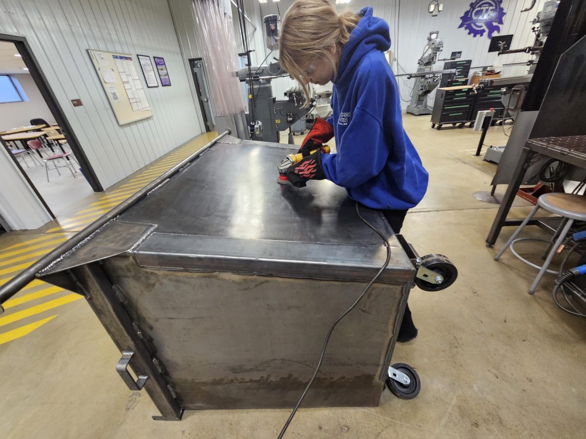Senior Emerson Struiksma wire-wheeling a dumpster before it is sent to get painted.