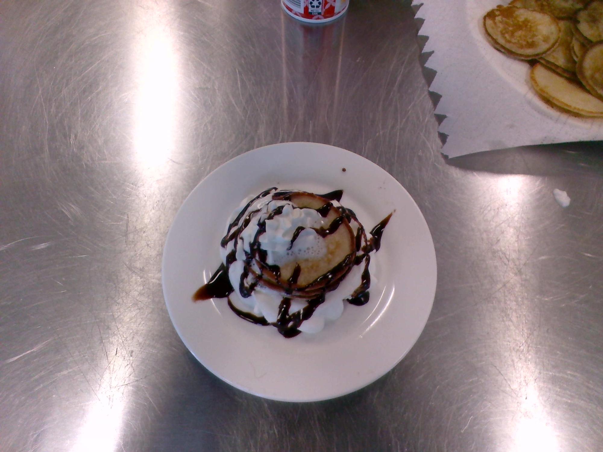 Russian Blini decorated with whipped cream and chocolate syrup.
