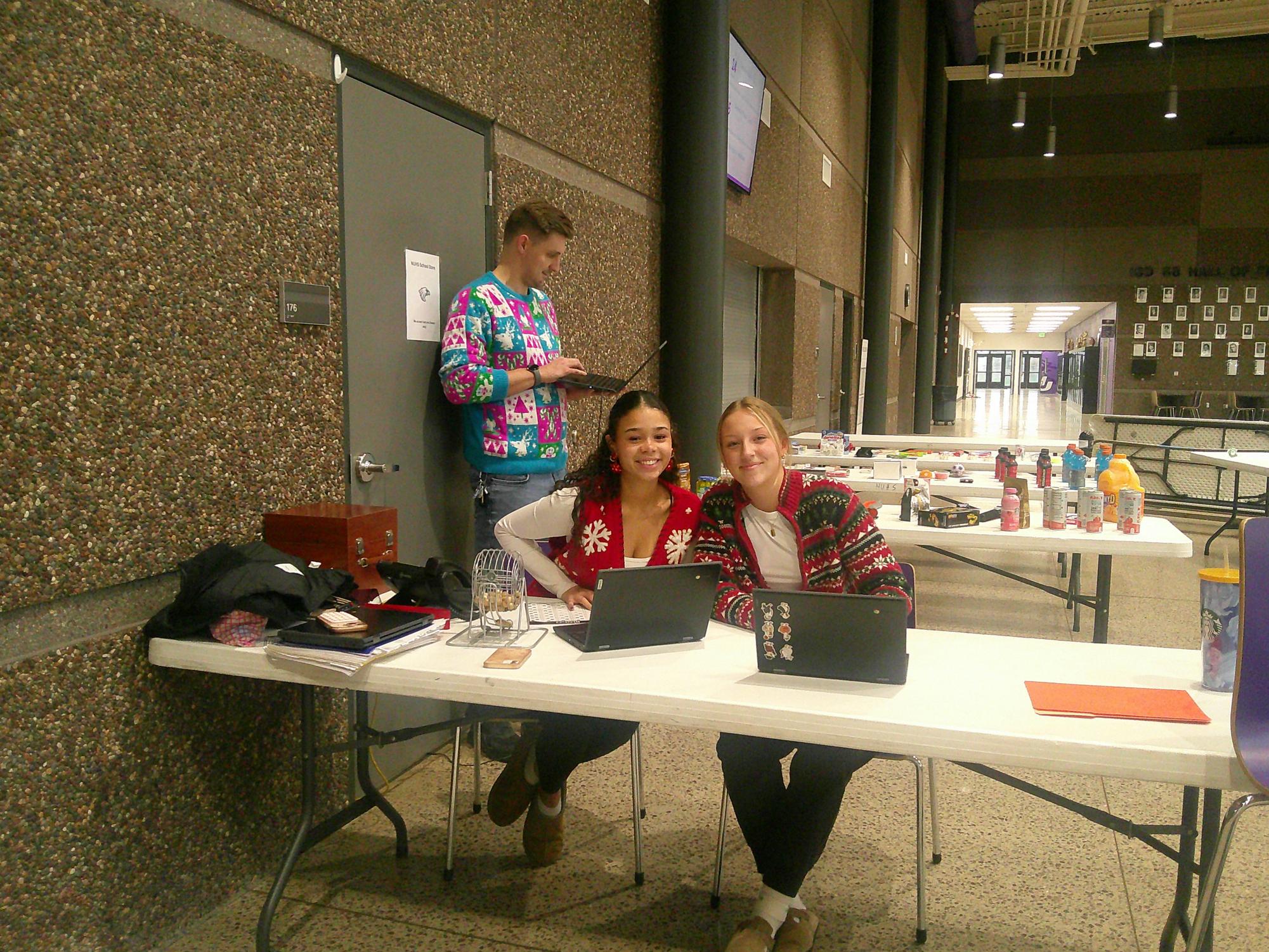 Student council members KayLee Evans (left) and Stella Fischer (right), and coordinator Mr. Nelson getting ready to call out numbers for turkey bingo.