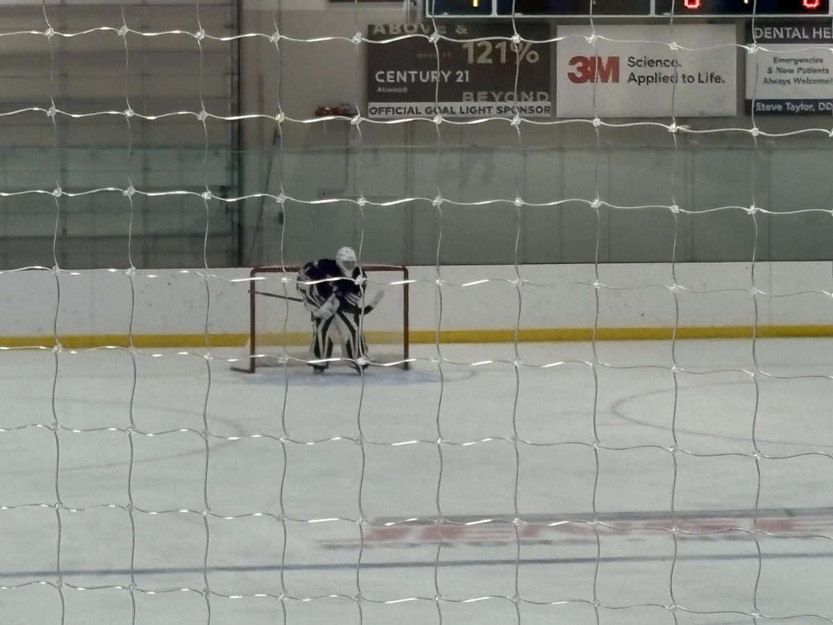 New Ulm goaltender Colton is watching the play from inside the net.