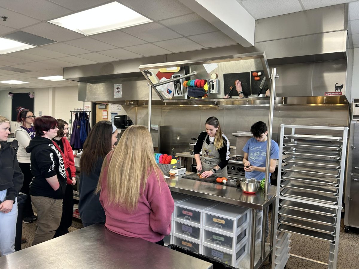 Miss.Schneider demonstrating safe cutting skills with Anthony assisting her