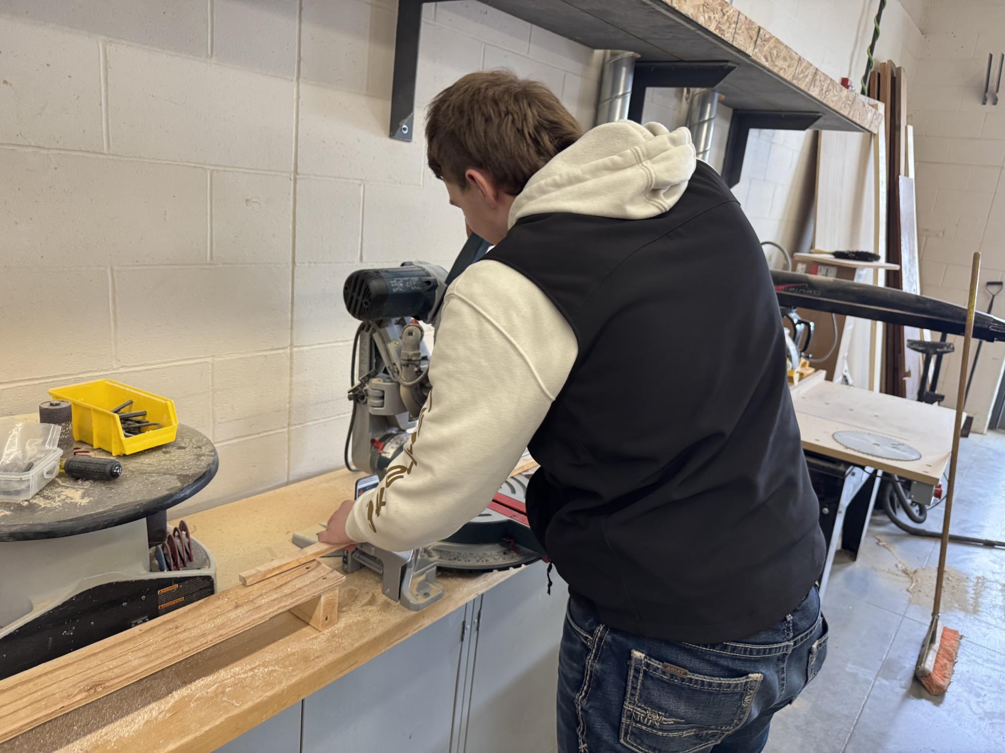 Senior Logan Platz cuts wood with miter box saw. 