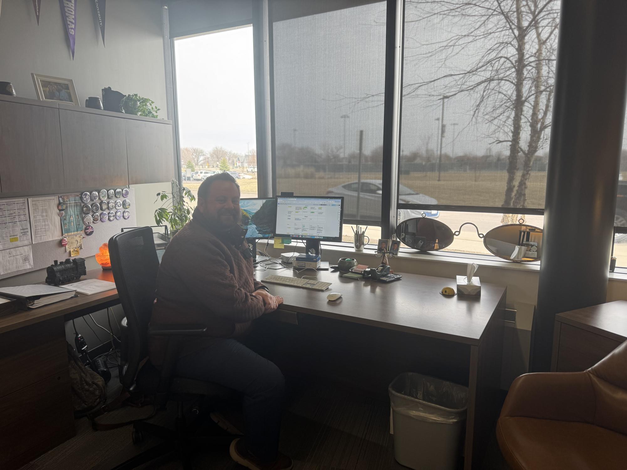 Mr. Ziemer sitting at his desk reviewing student registration numbers for new online classes at New Ulm High School.