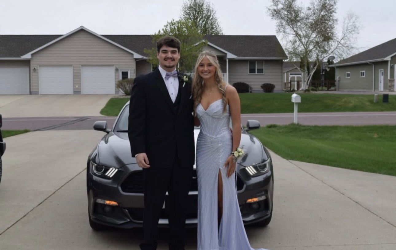 Tanner Backer and Lily Poehler pose for a picture in front of a Ford mustang that they drove to prom.