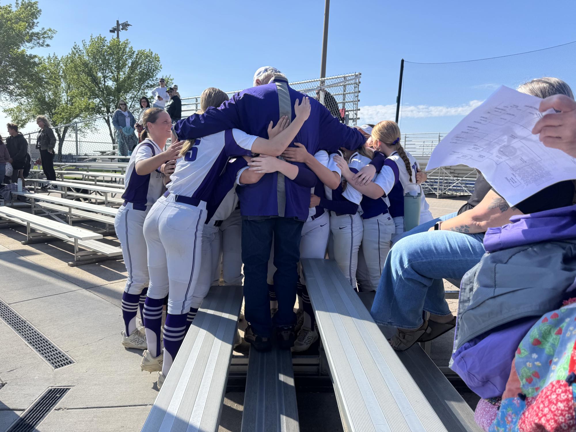Softball girls huddle around their bus driver Steve 